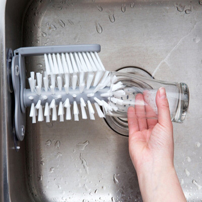 Kitchen bottle brush head with white bristles and gray holder, cleaning a glass bottle