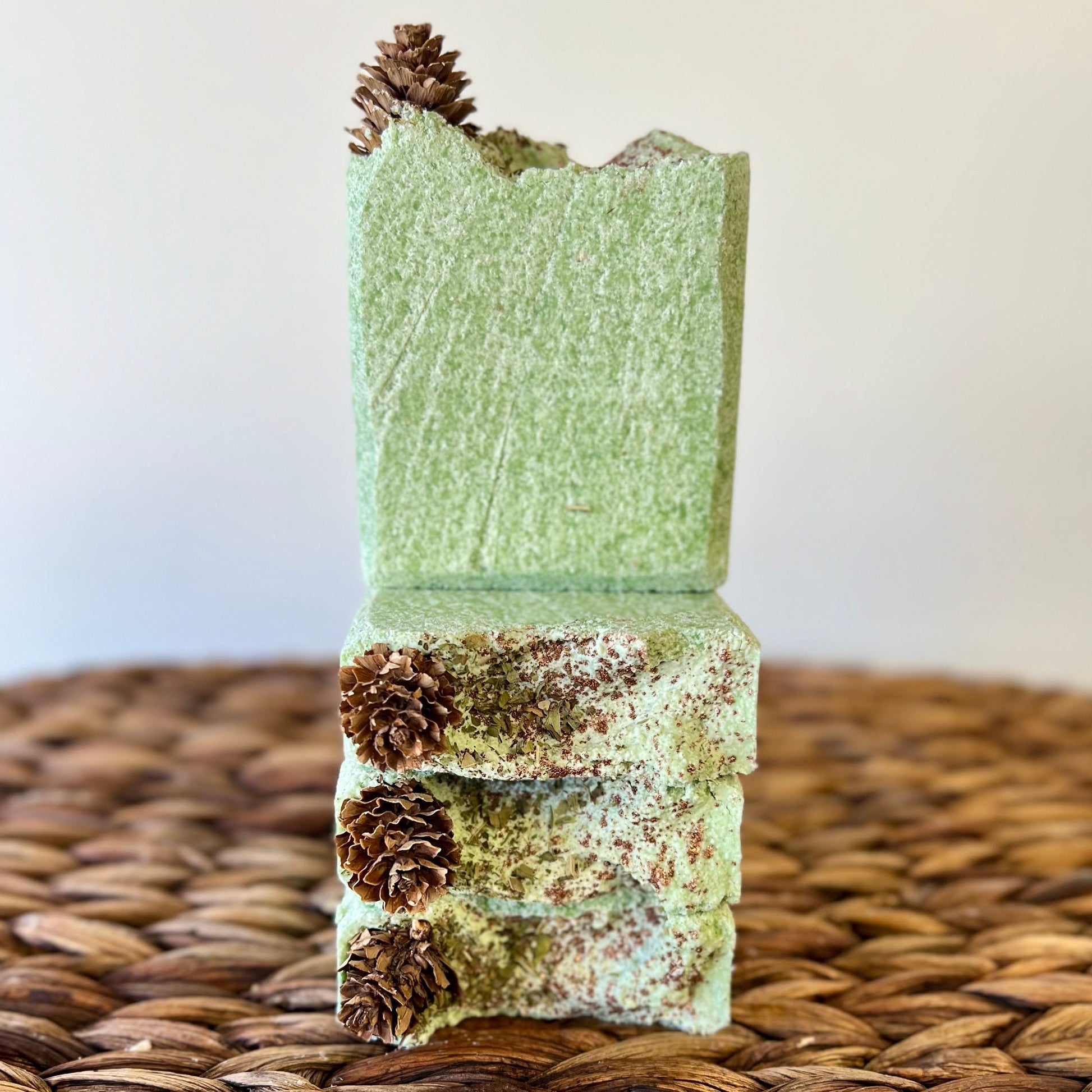 Vertical stack of green sea salt soap bars with pinecone accents