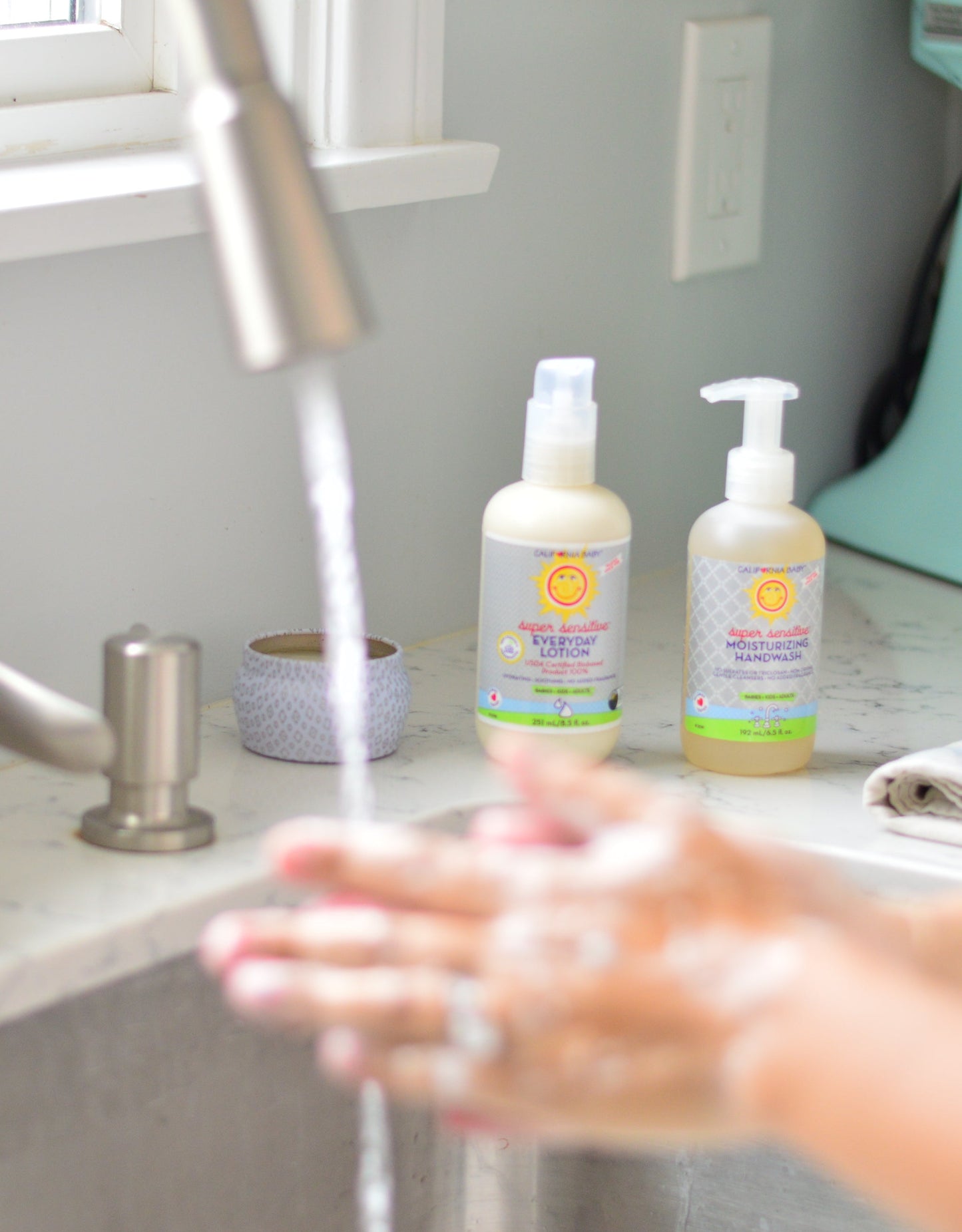 Pump bottles on bathroom sink counter with hands lathering under water
