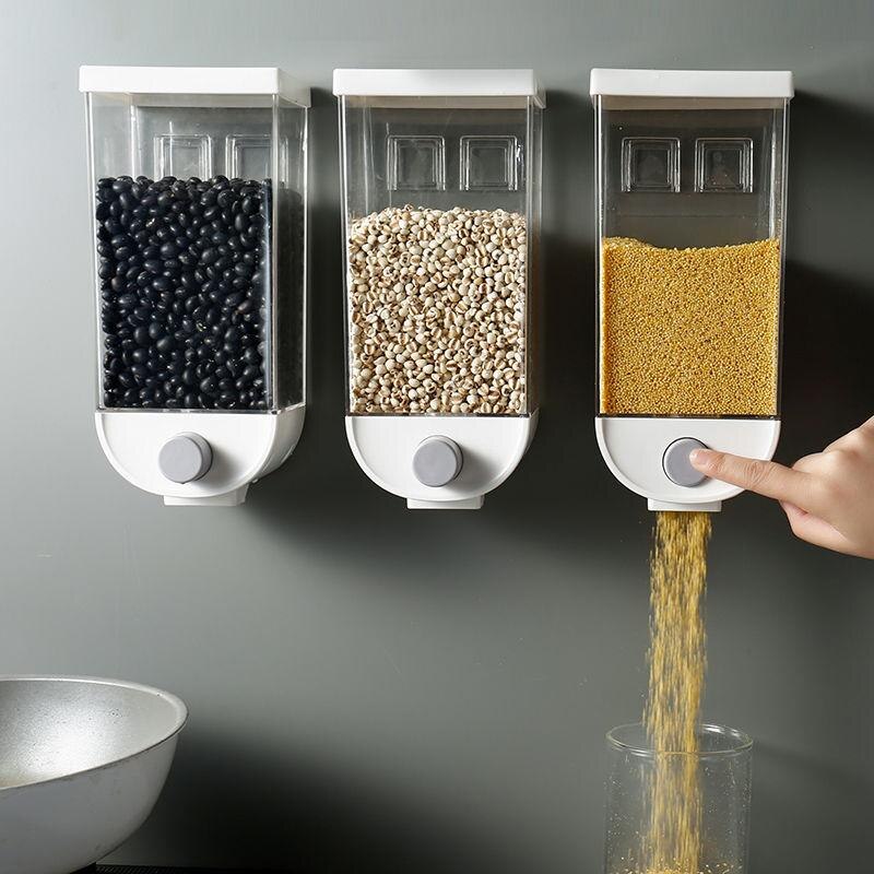Wall-mounted kitchen sealed grain jars, three clear bins with dark, beige, and yellow kernels