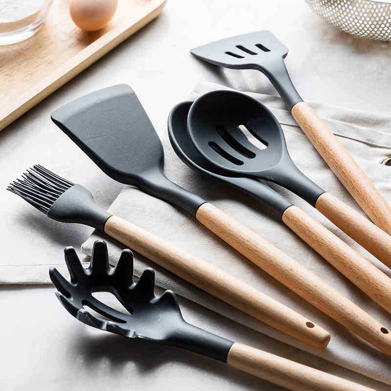 Black silicone cooking utensils with wooden handles, including spatula and spoon tools