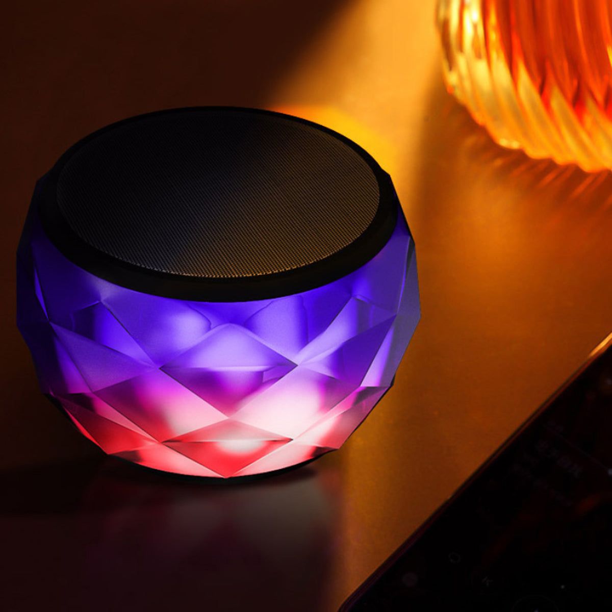 Mini LED Bluetooth speaker with purple and orange faceted glow, black top grille