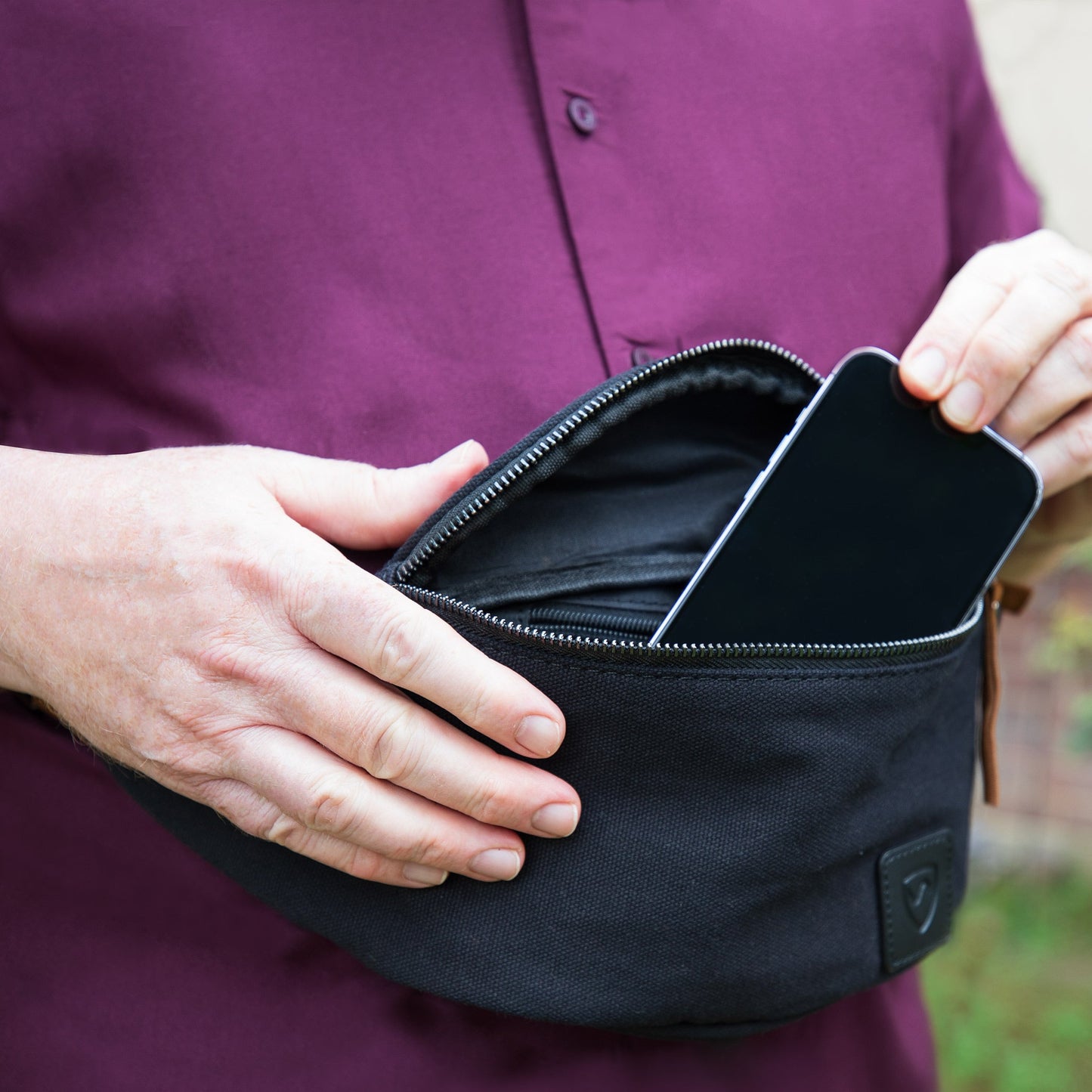 Canvas crossbody fanny pack, black; open zipper pocket shown in hand