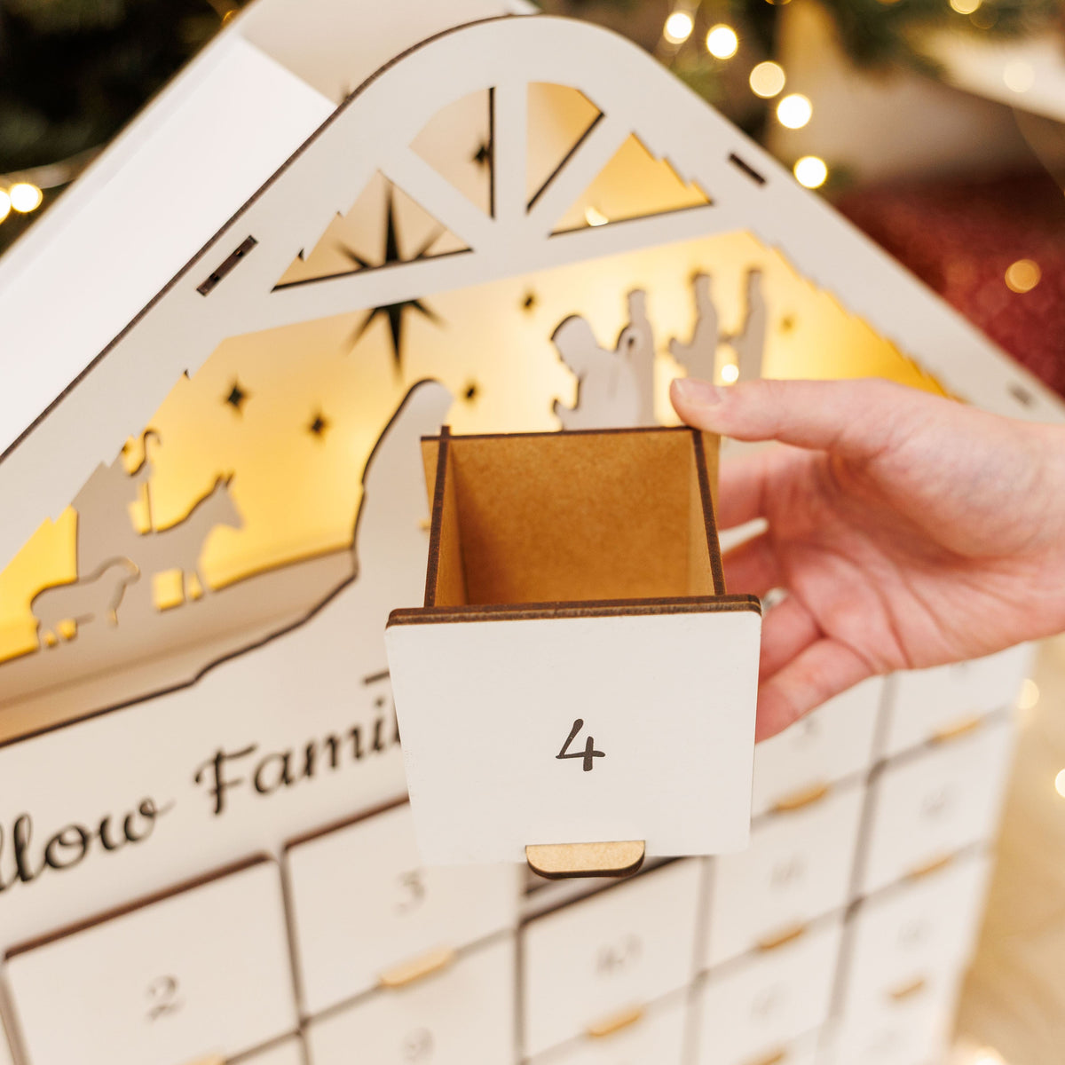 White advent calendar drawer being opened, numbered slot 4 with gold handle