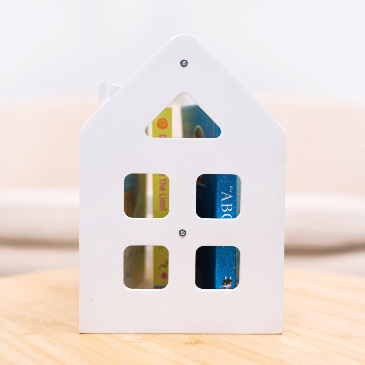 White house-shaped Montessori book shelf with four rectangular book-window openings