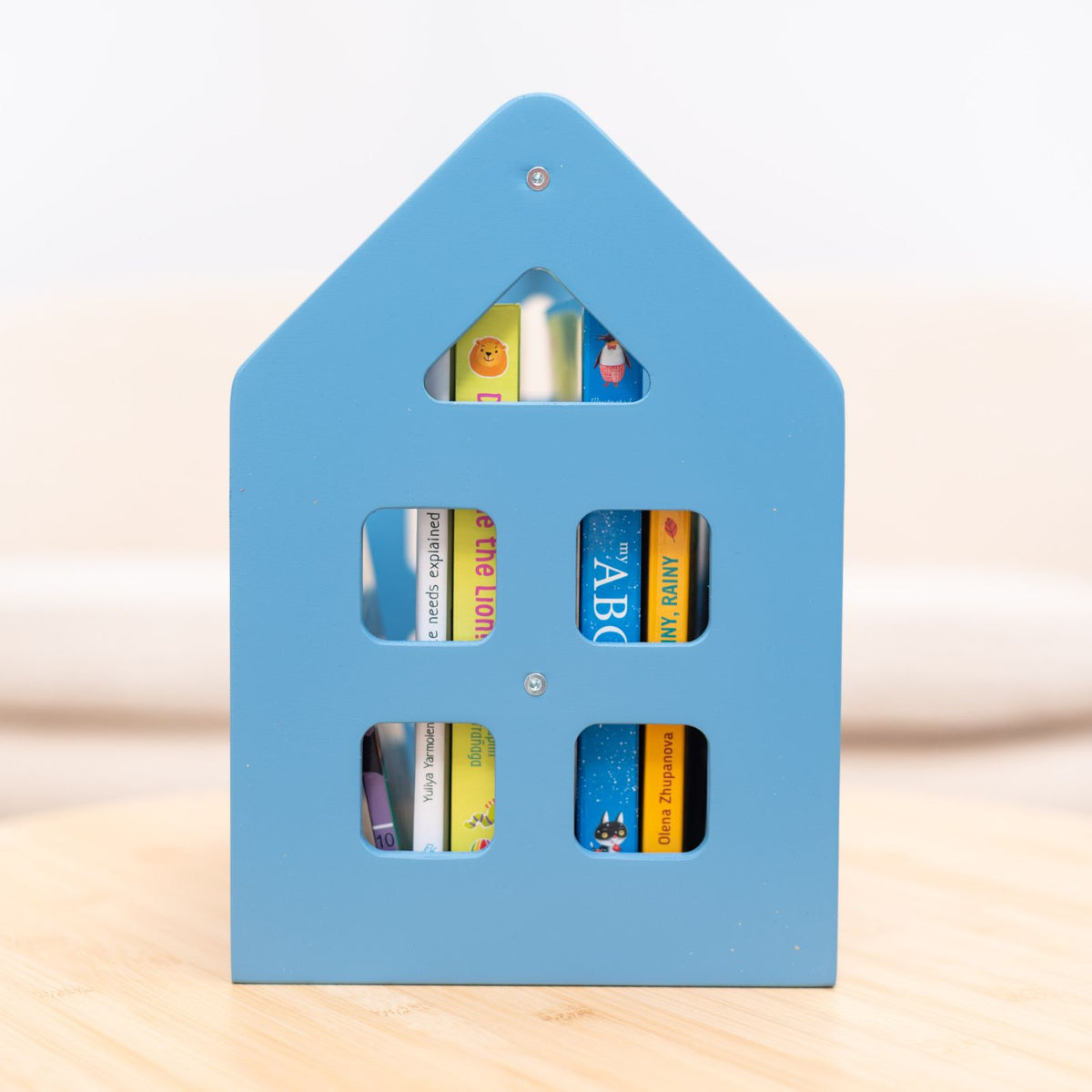 Blue house-shaped Montessori book shelf with four rectangular book-window openings
