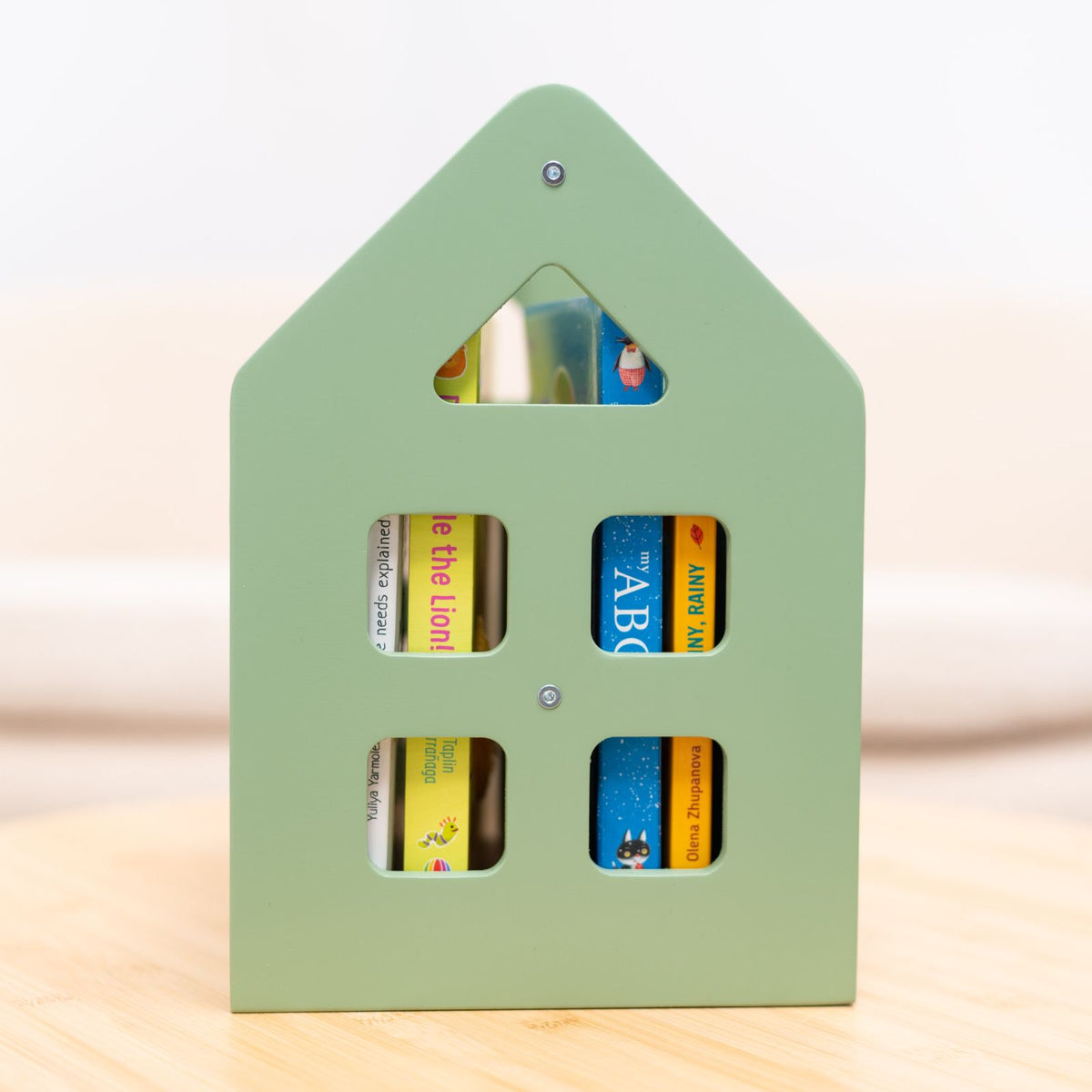 Olive green house-shaped Montessori book shelf with four rectangular book-window openings