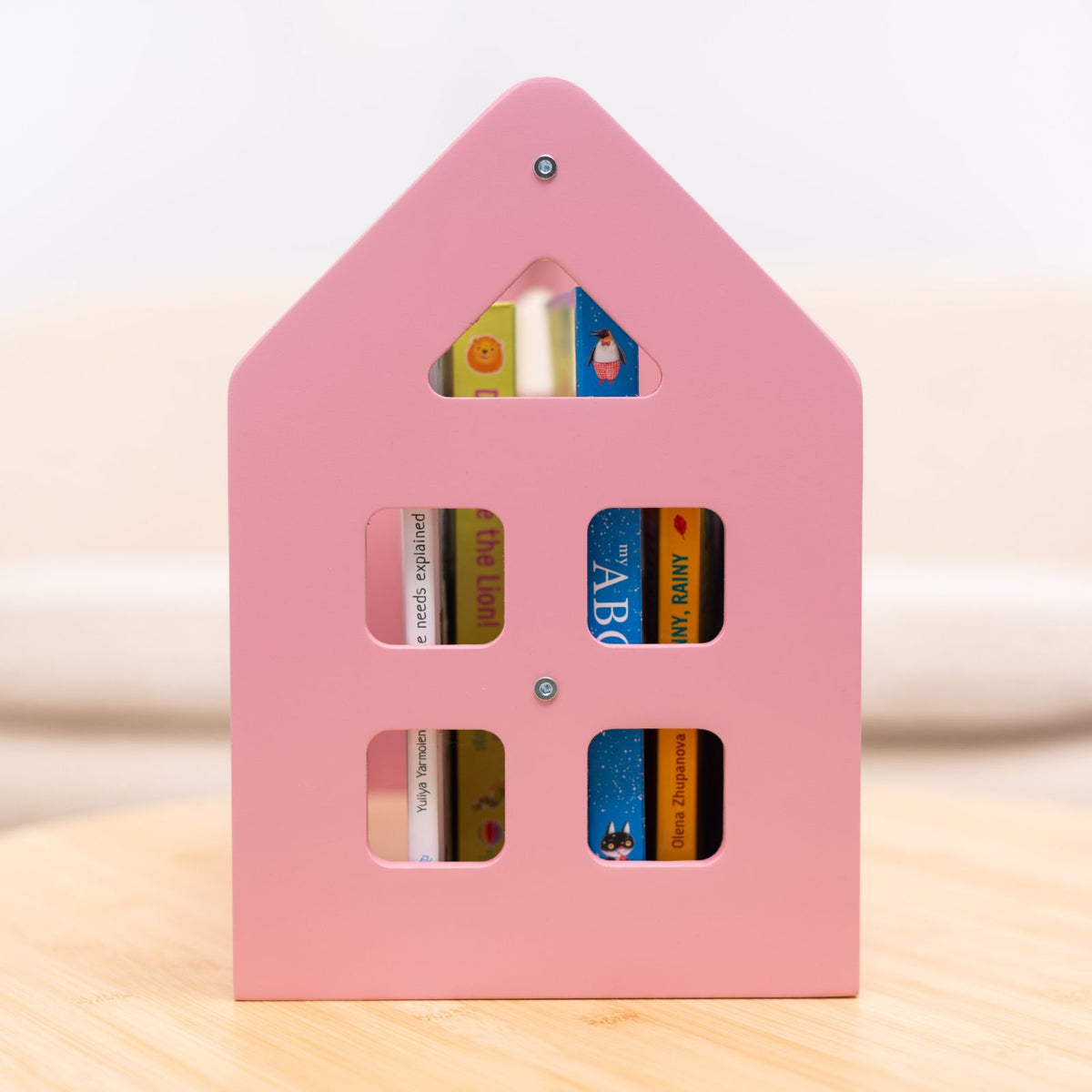 Pink house-shaped book shelf with six cubby slots for children’s books