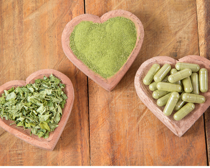 Moringa oleifera powder in heart bowls with green veggie capsules