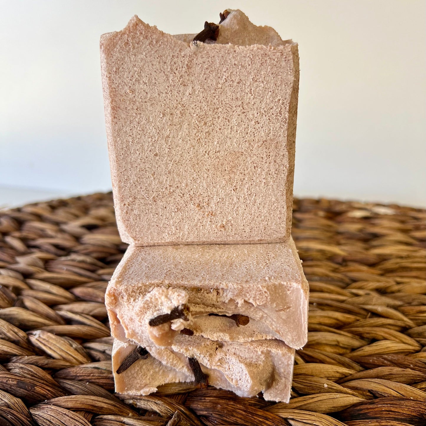 Beige sea salt soap bar with visible dark chunks, shown upright on woven mat.