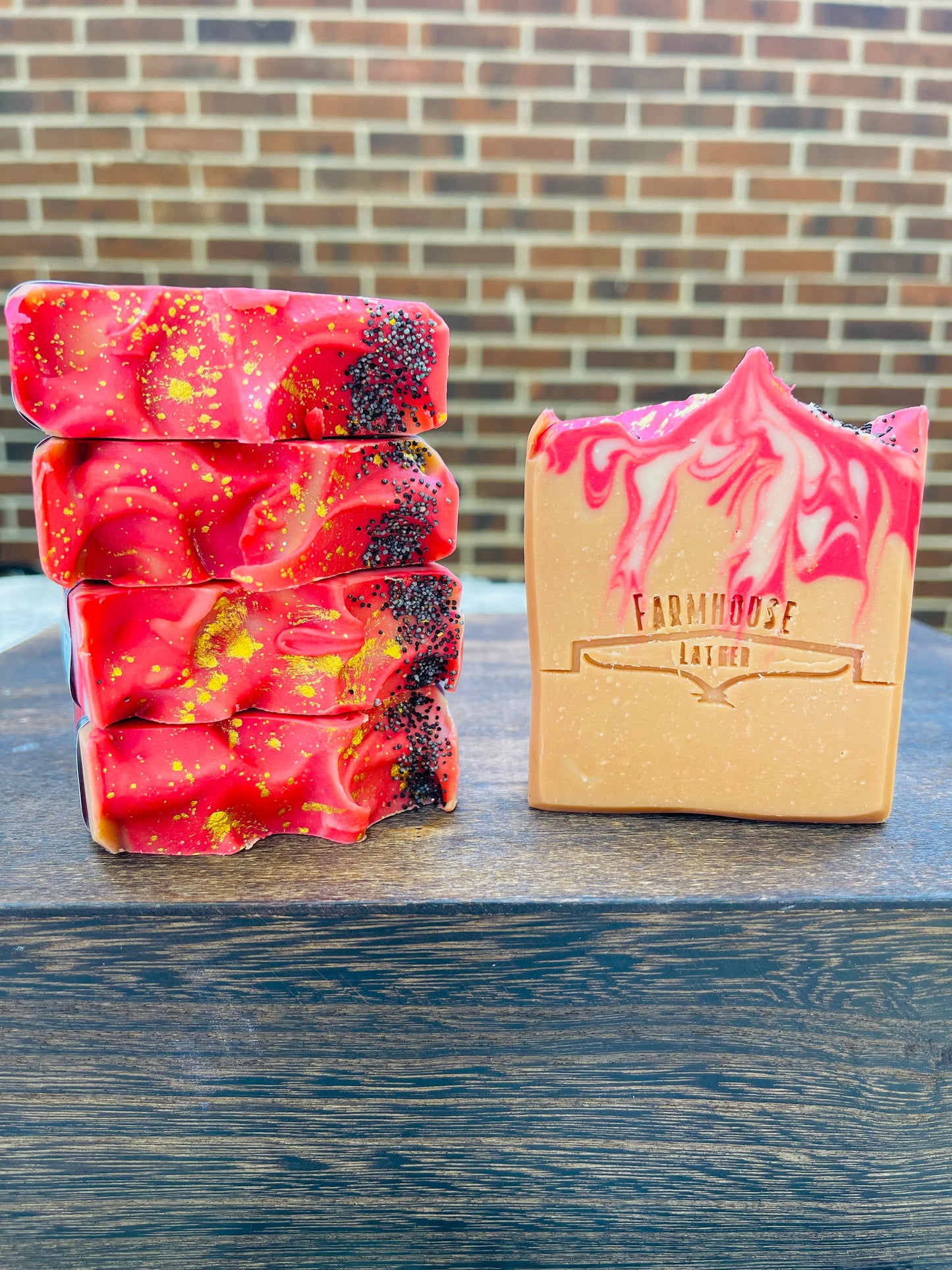 Stacked red speckled soap bars and a yellow boxed soap on wood