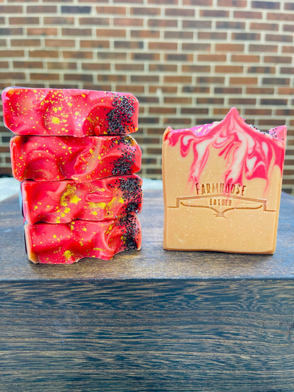 Stacked red speckled soap bars and a yellow boxed soap on wood