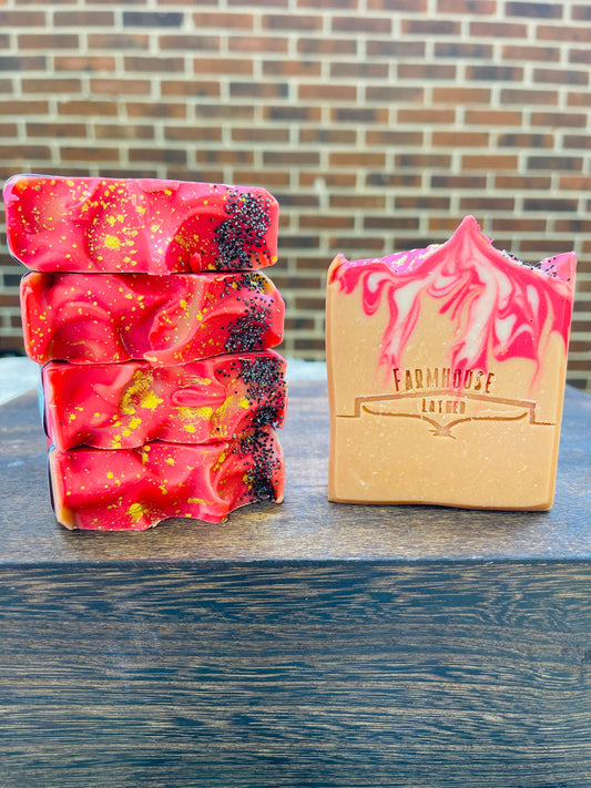 Stacked red speckled soap bars and a yellow boxed soap on wood
