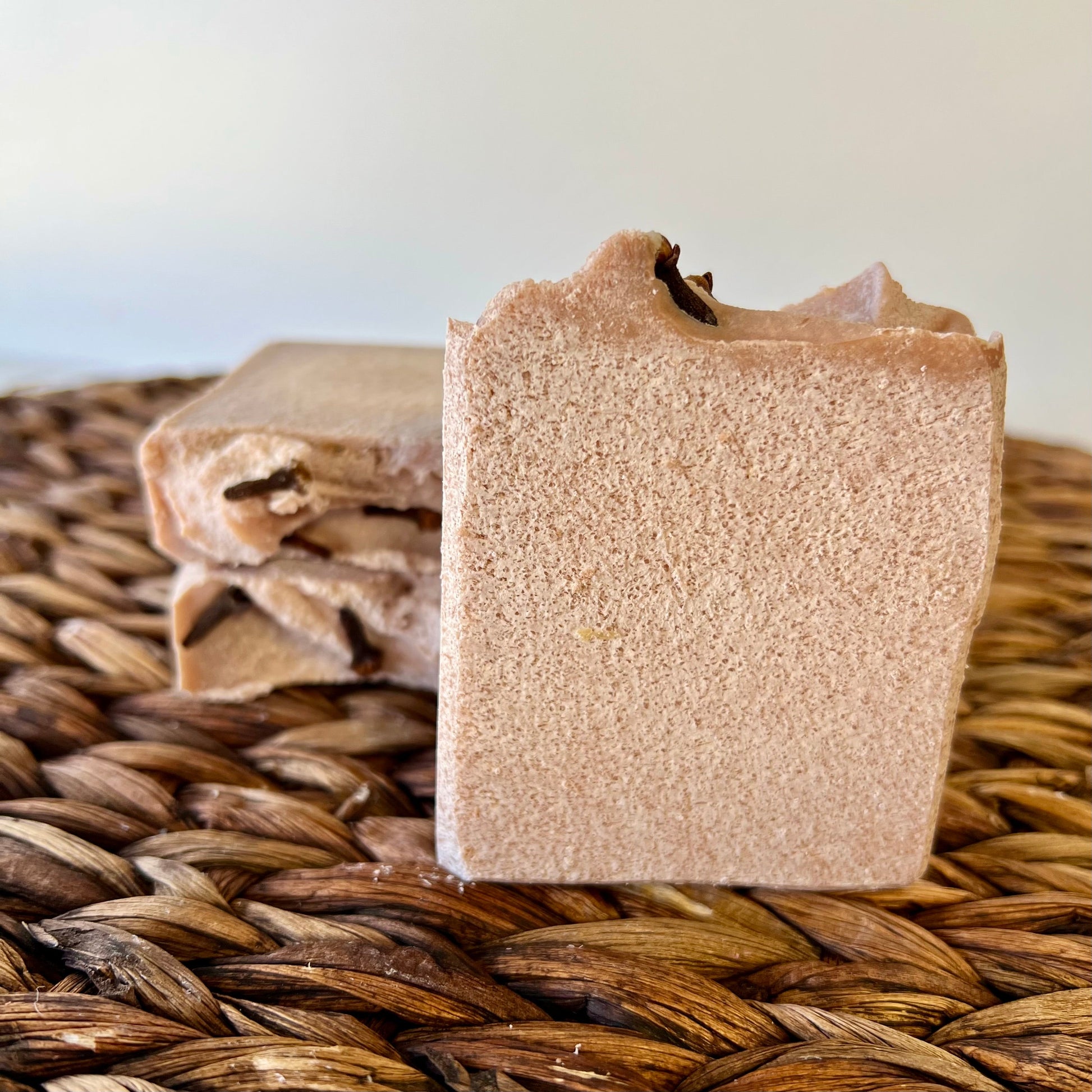Beige sea salt soap bar with dark top piece, with smaller bars in background on mat.