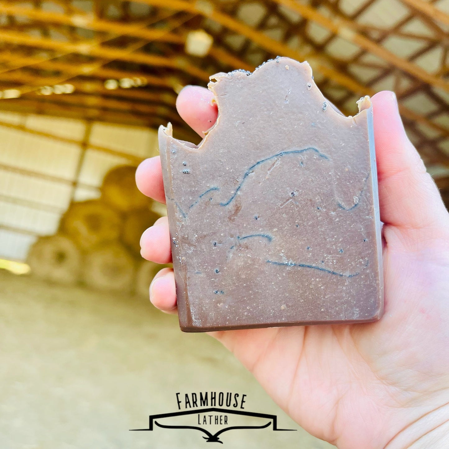 Soap bar with dusty blue top and brown center, held in a hand