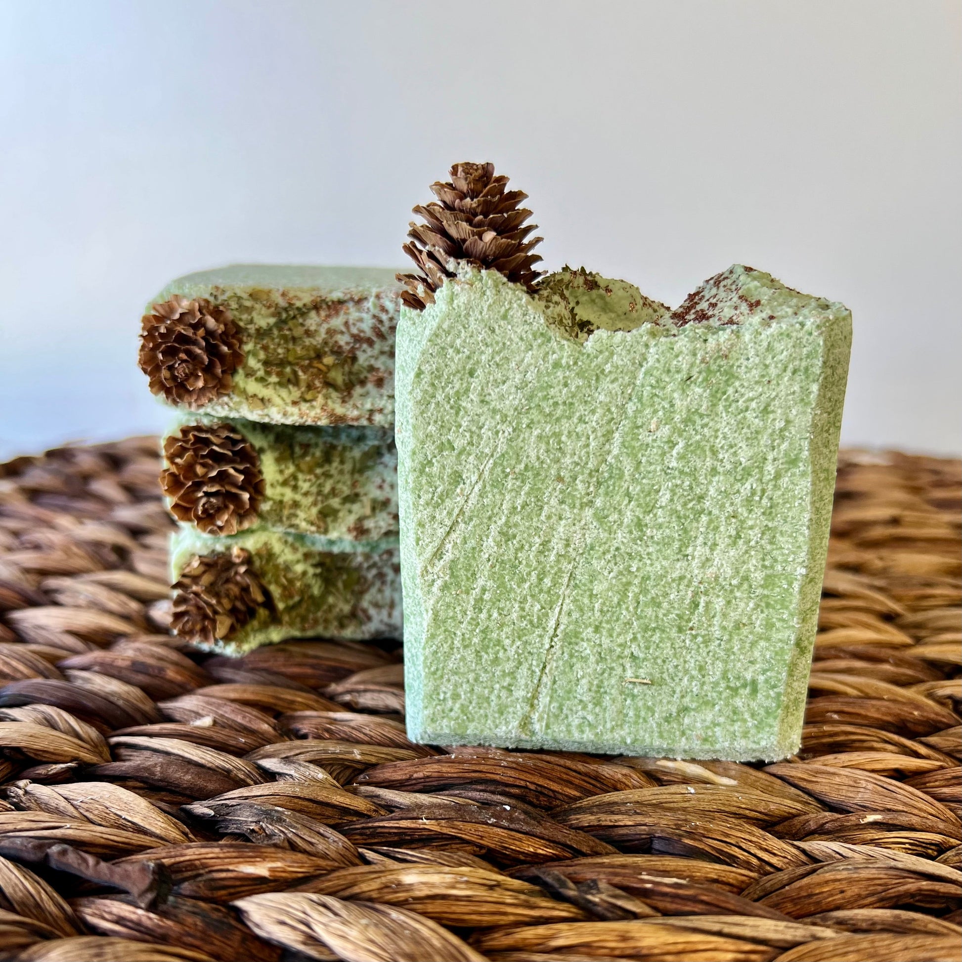 Green sea salt soap bar with pinecone topper on woven straw mat