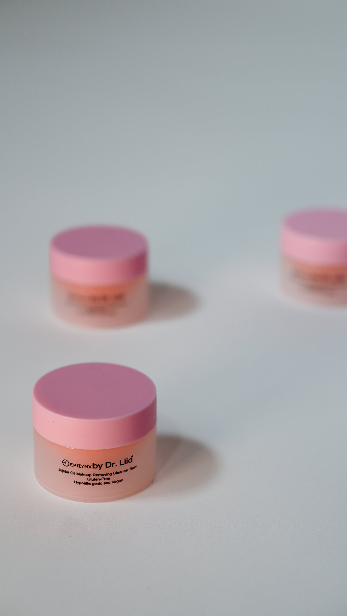 Mini jars of peach makeup remover balm with purple-pink lids