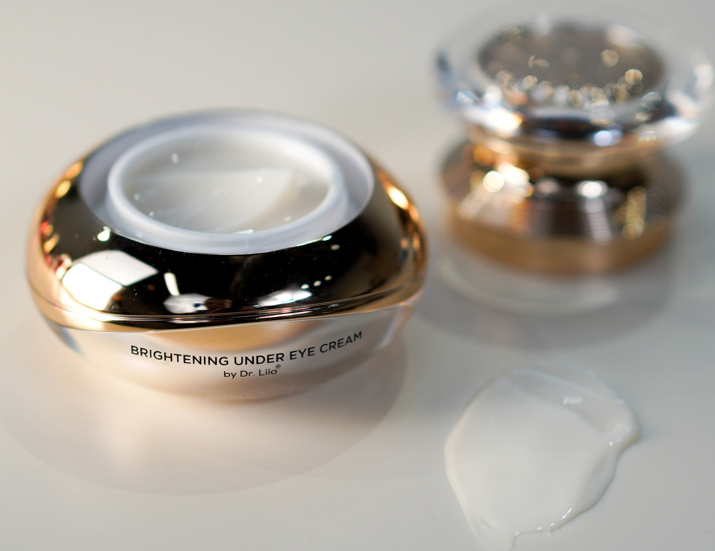 Under eye cream jar with white cream shown and a second lid in background.