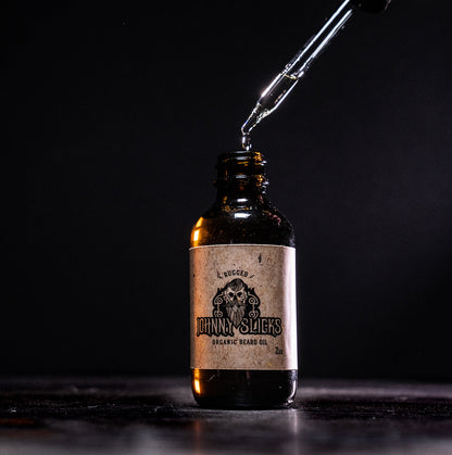 Organic beard oil bottle with black dropper; amber bottle with oil stream pouring.