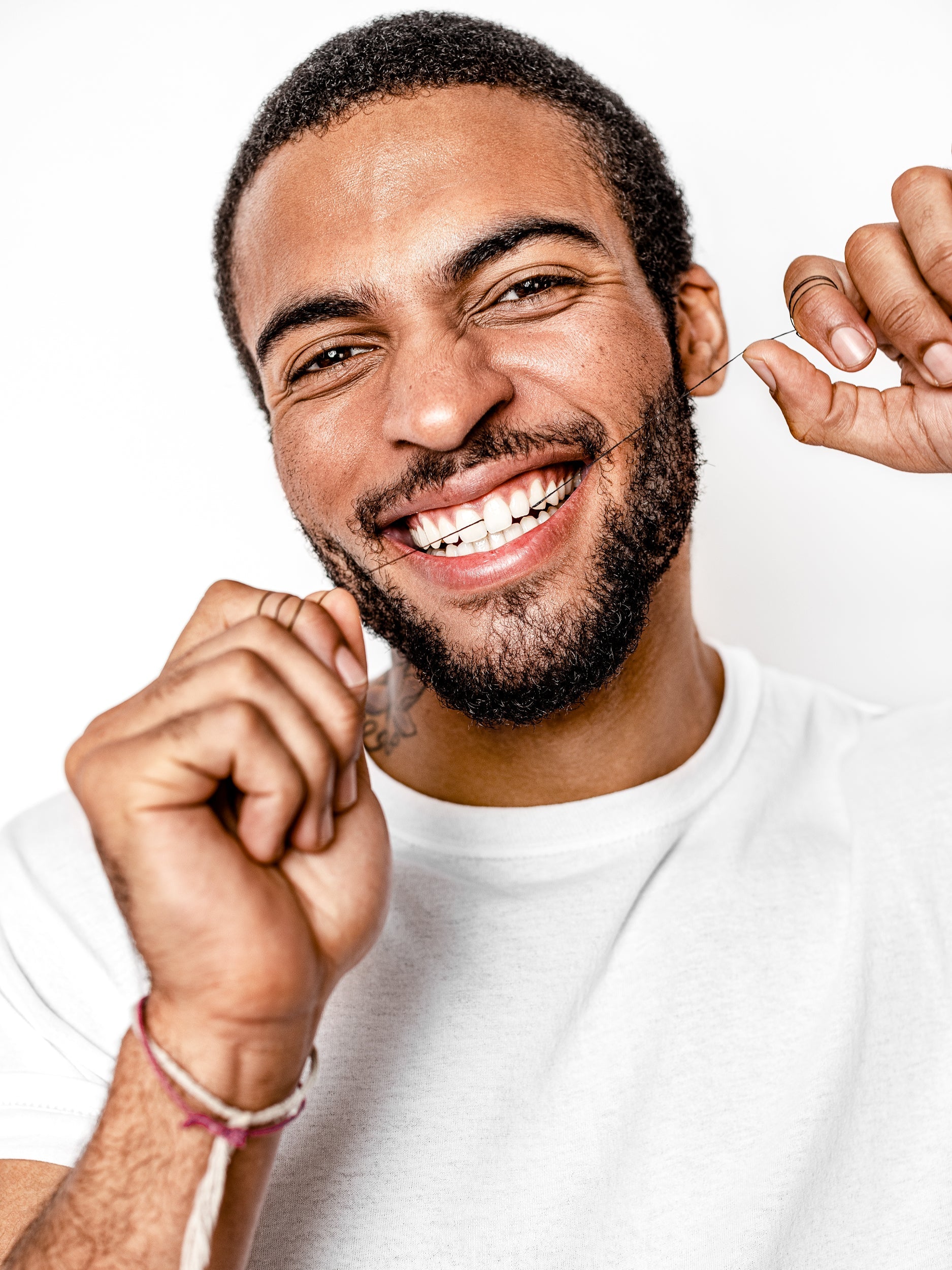 Man smiling while pulling dental floss string near teeth
