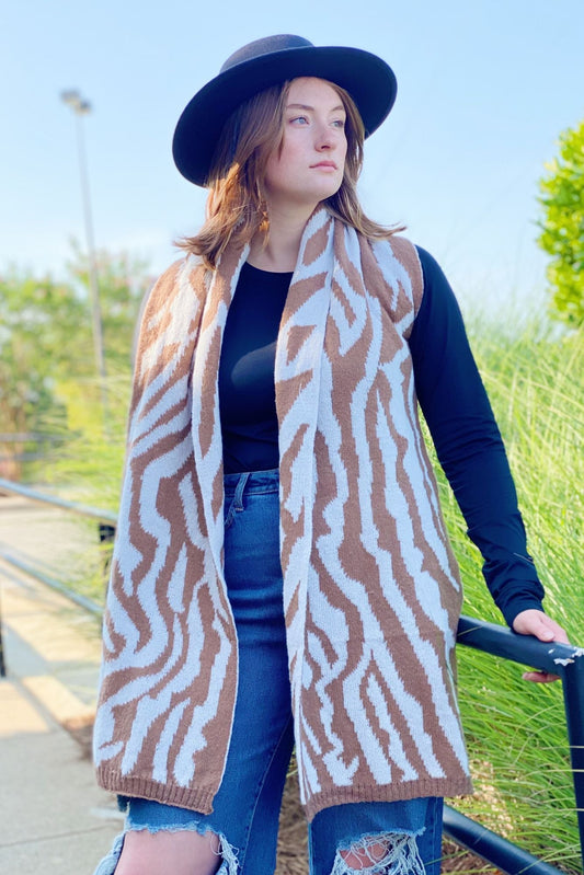 Zebra-pattern scarf draped over shoulders, tan and white knit with fringed hem