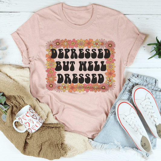 Dusty peach crewneck T-shirt with floral-bordered distressed “Depressed but well dressed” text