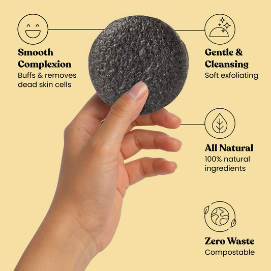 Charcoal facial cleansing sponge held in hand, round dark gray exfoliating pad