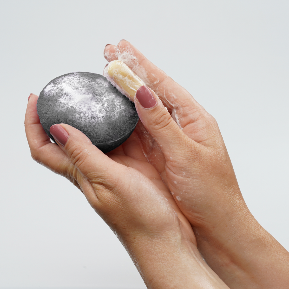 Charcoal facial cleansing sponge with lather, held in hands