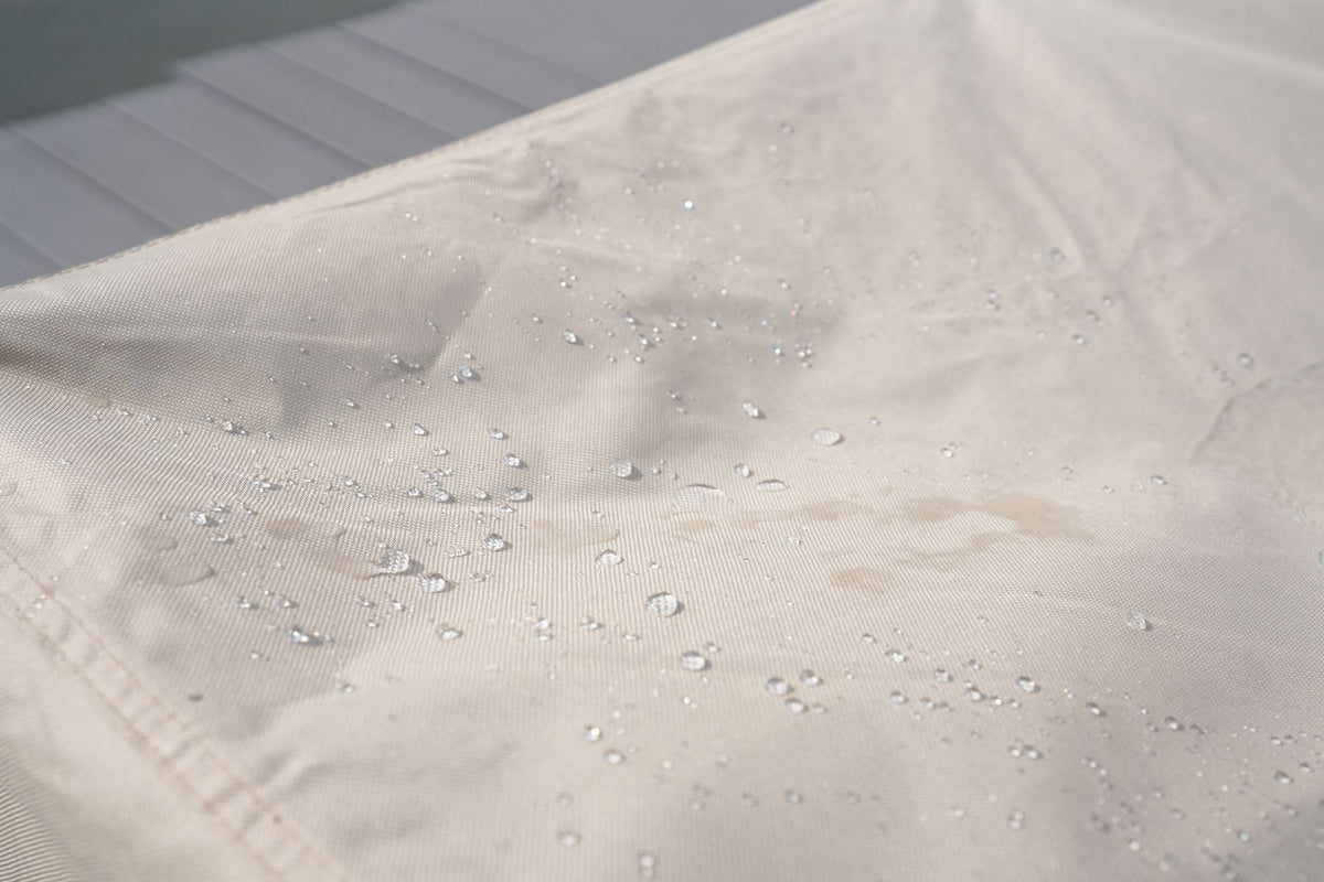 Water-resistant beige fabric surface on patio sofa cover with water droplets