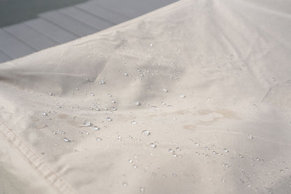 Water-resistant beige fabric surface on patio sofa cover with water droplets