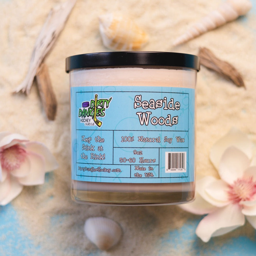Seaside Woods soy wax candle in clear glass jar with blue Dirty Dangles label and black lid
