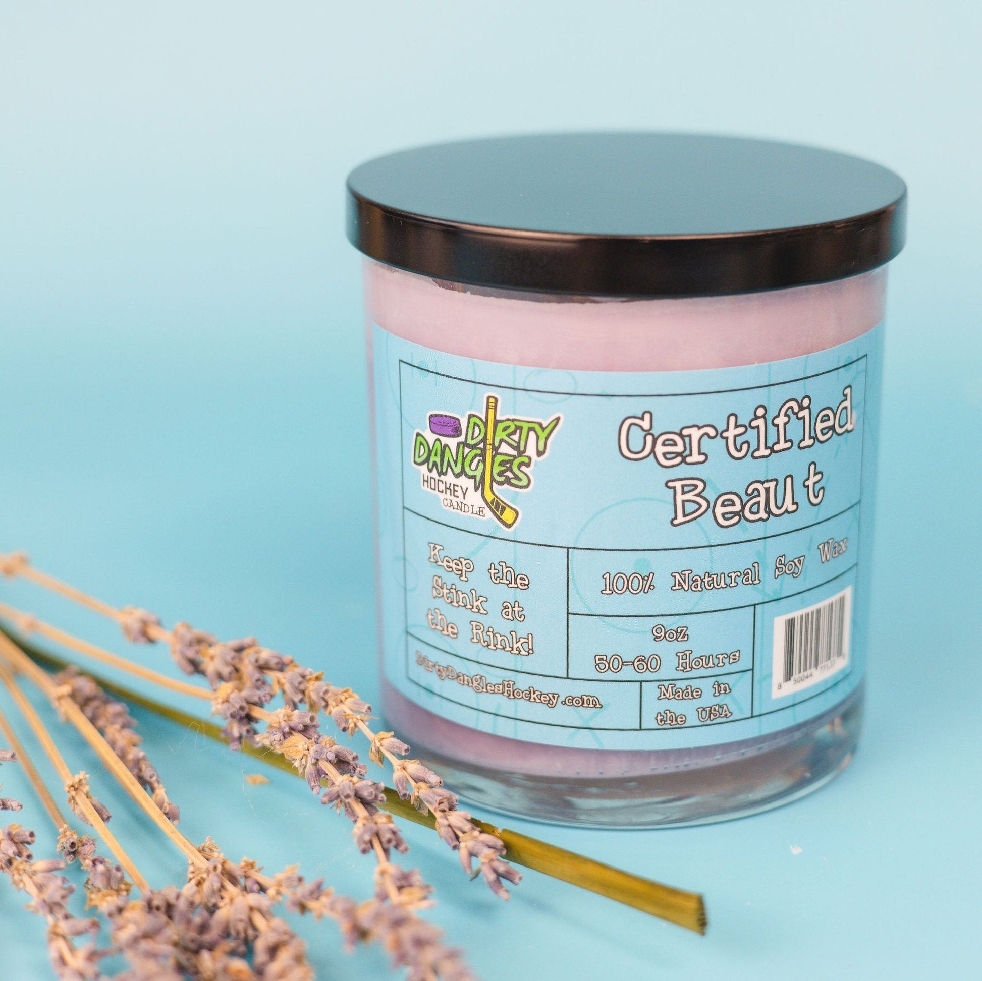 Lavender-pink candle in glass jar with black lid, colorful front label text