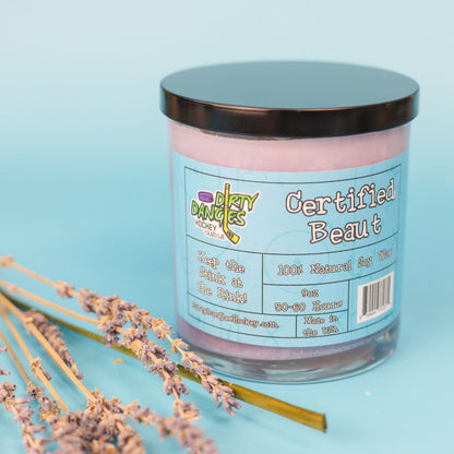 Lavender-pink candle in glass jar with black lid, colorful front label text