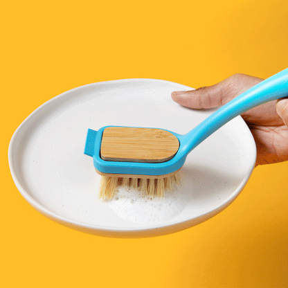 Blue dish brush scrubbing a white bowl with light yellow bristles