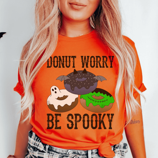 Orange crewneck T-shirt with bat-and-donut graphic and 'Be Spooky' text