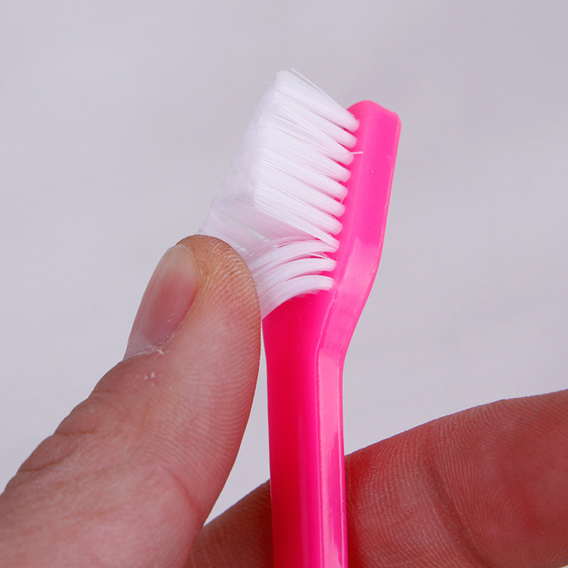 Pink pet finger toothbrush with dual brush heads and white bristles, held in hand