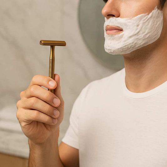 Gold double-sided safety razor held in hand