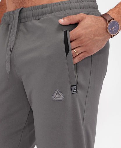 Gray tapered athletic sweatpants with elastic waistband and logo patch at thigh
