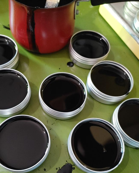 Set of open salve jars with dark charcoal balm on a tabletop