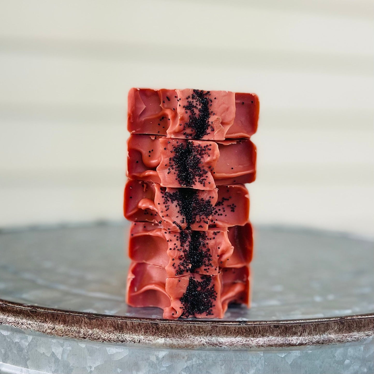 Stacked handmade soap bars, deep red with black speckles on top