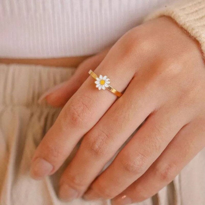 Gold daisy fidget spinner ring on finger, white flower with yellow center