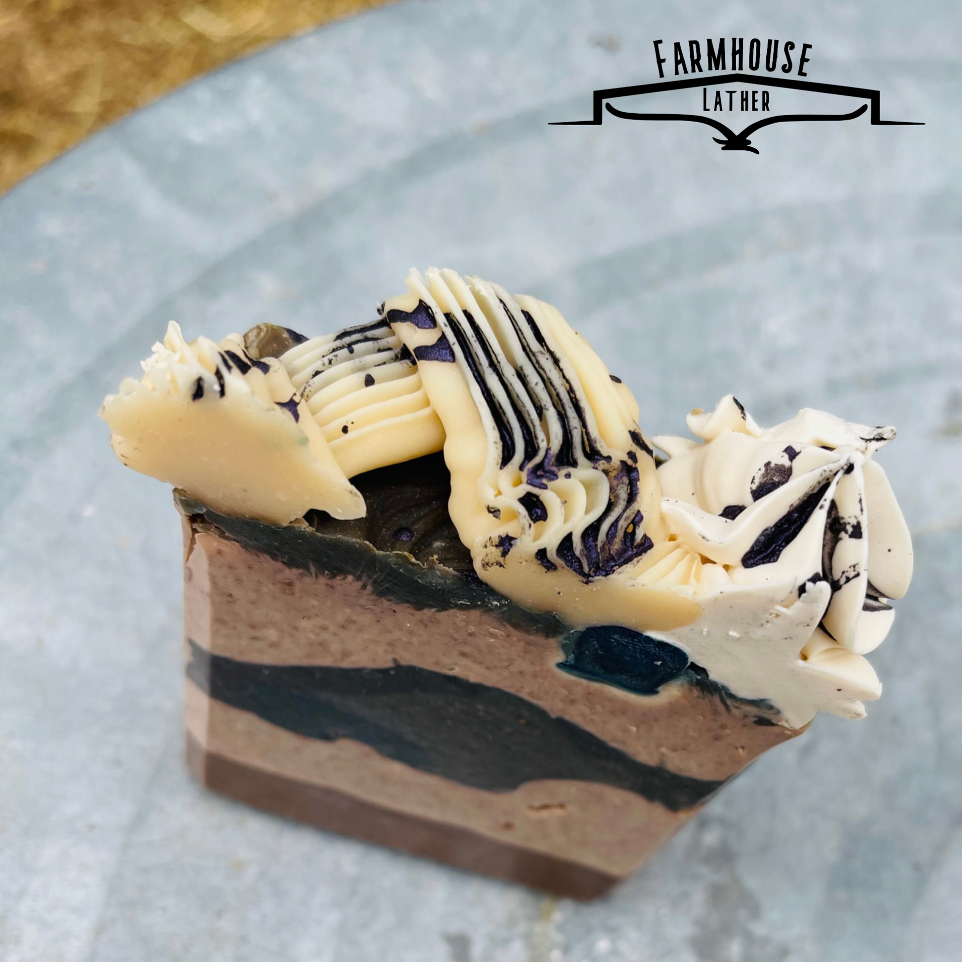 Handmade soap bar with black-blue stripe layers and white swirl topping