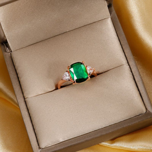 Rose gold square solitaire ring with green gemstone and small clear side stones