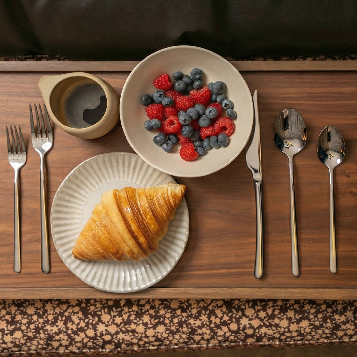 Silver flatware set on a tray with forks, knives, and spoons beside plates