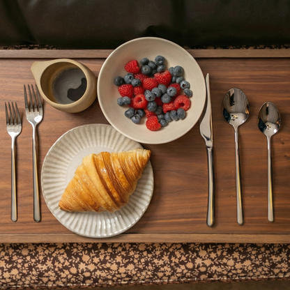 Silver flatware set on a tray with forks, knives, and spoons beside plates