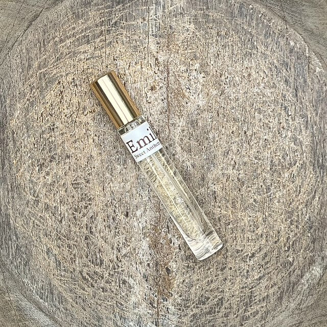 Emily perfume spray bottle tilted, gold cap and clear glass with pale yellow liquid
