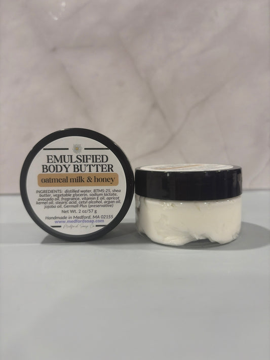 Emulsified body butter jar with black lid, creamy off-white butter.