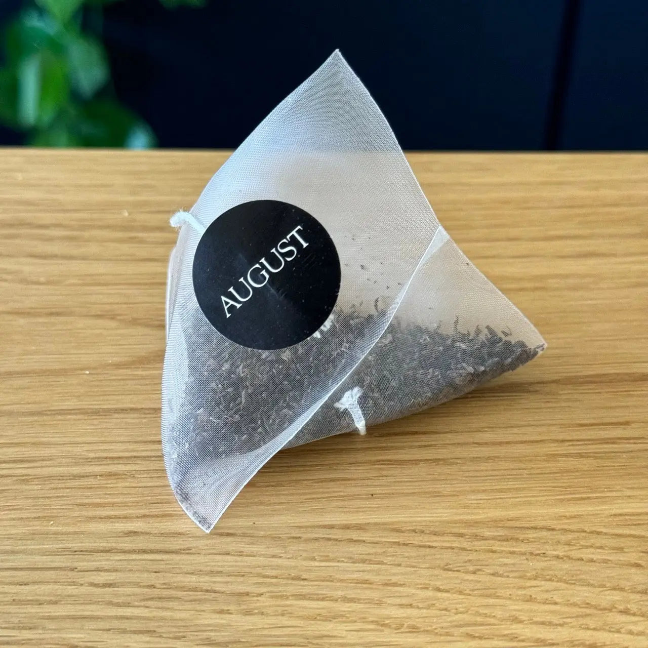 August black tea bag sachet with dark tea leaves, sealed in foil pouch