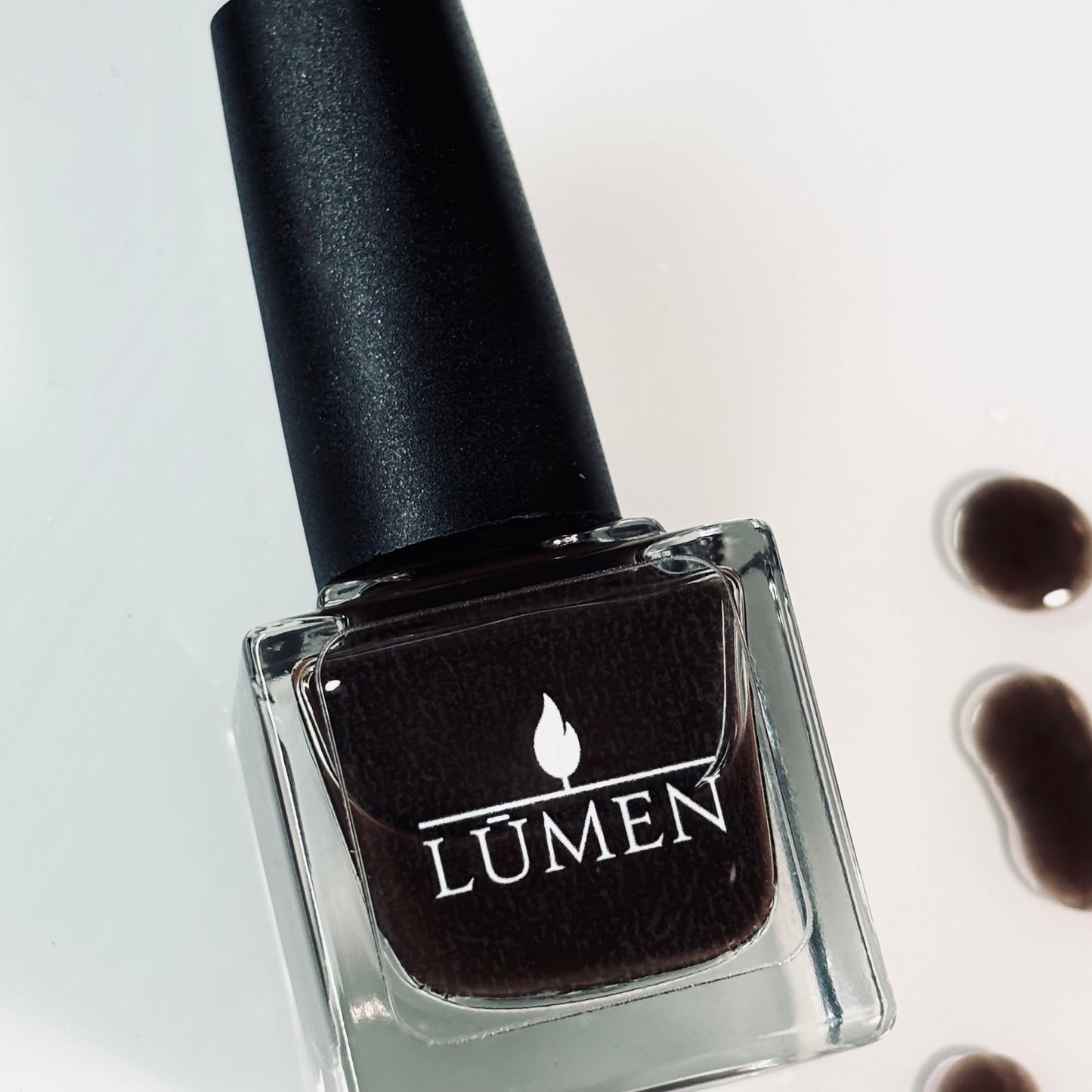 LUMEN nail polish bottle with black cap, dark espresso-brown polish in glass.