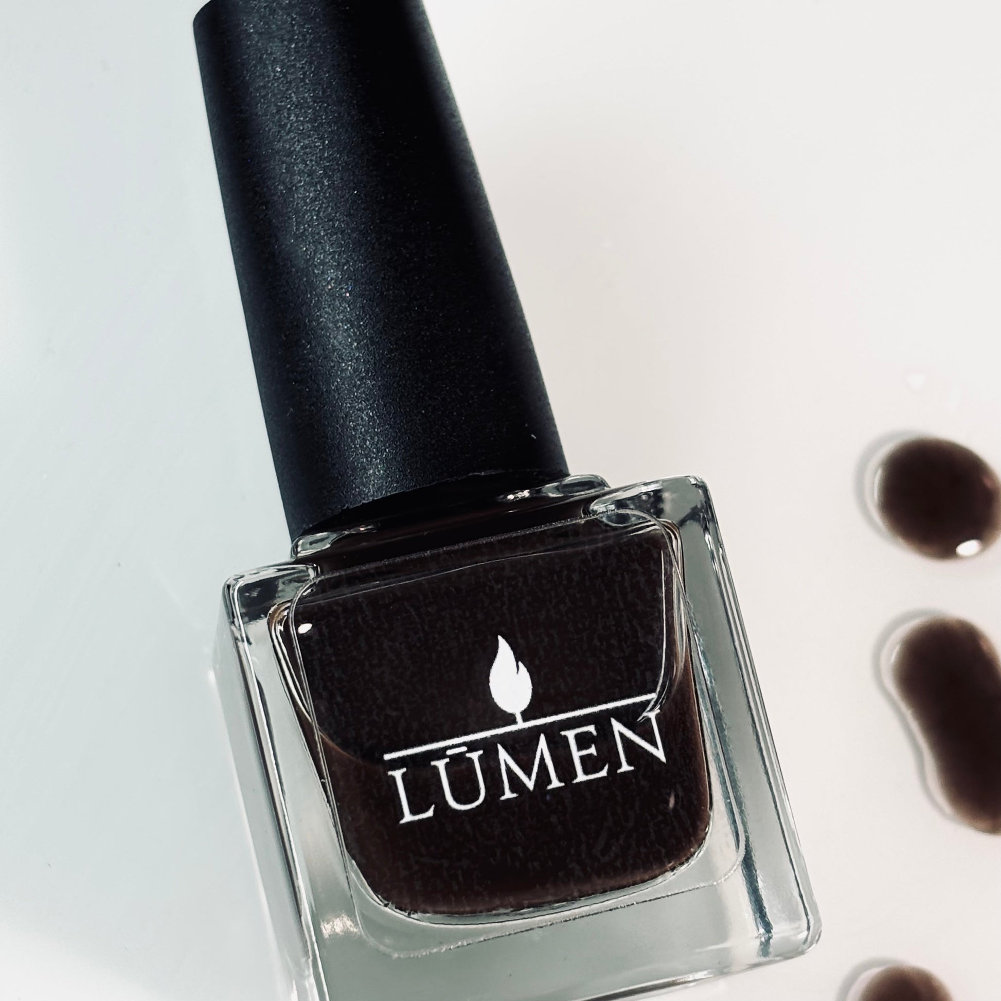 LUMEN nail polish bottle with black cap, dark espresso-brown polish in glass.